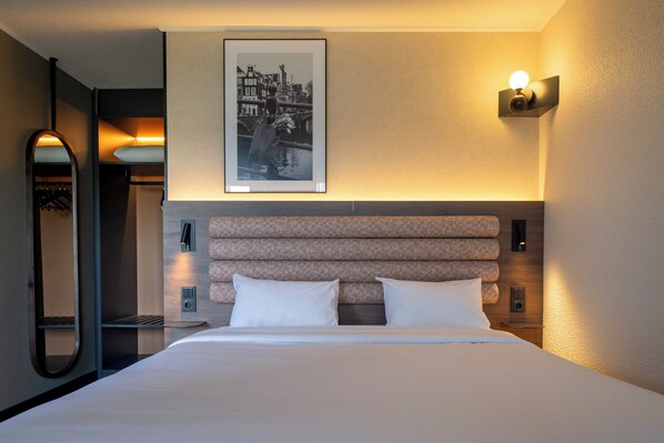 A hotel room with a bed, a framed picture on the wall, and a light fixture. - Campanile Hotel Gouda (Gouda)