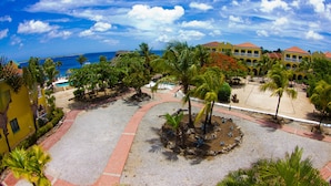 A resort with a pool, palm trees, and a view of the ocean. - Buddy Dive Resort (Kralendijk)