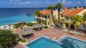 A resort with a pool area, a beach view, and a boat in the water. - Buddy Dive Resort (Kralendijk)