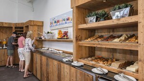 A buffet area with wooden cabinets and shelves displaying various food items. - Buddy Dive Resort (Kralendijk)