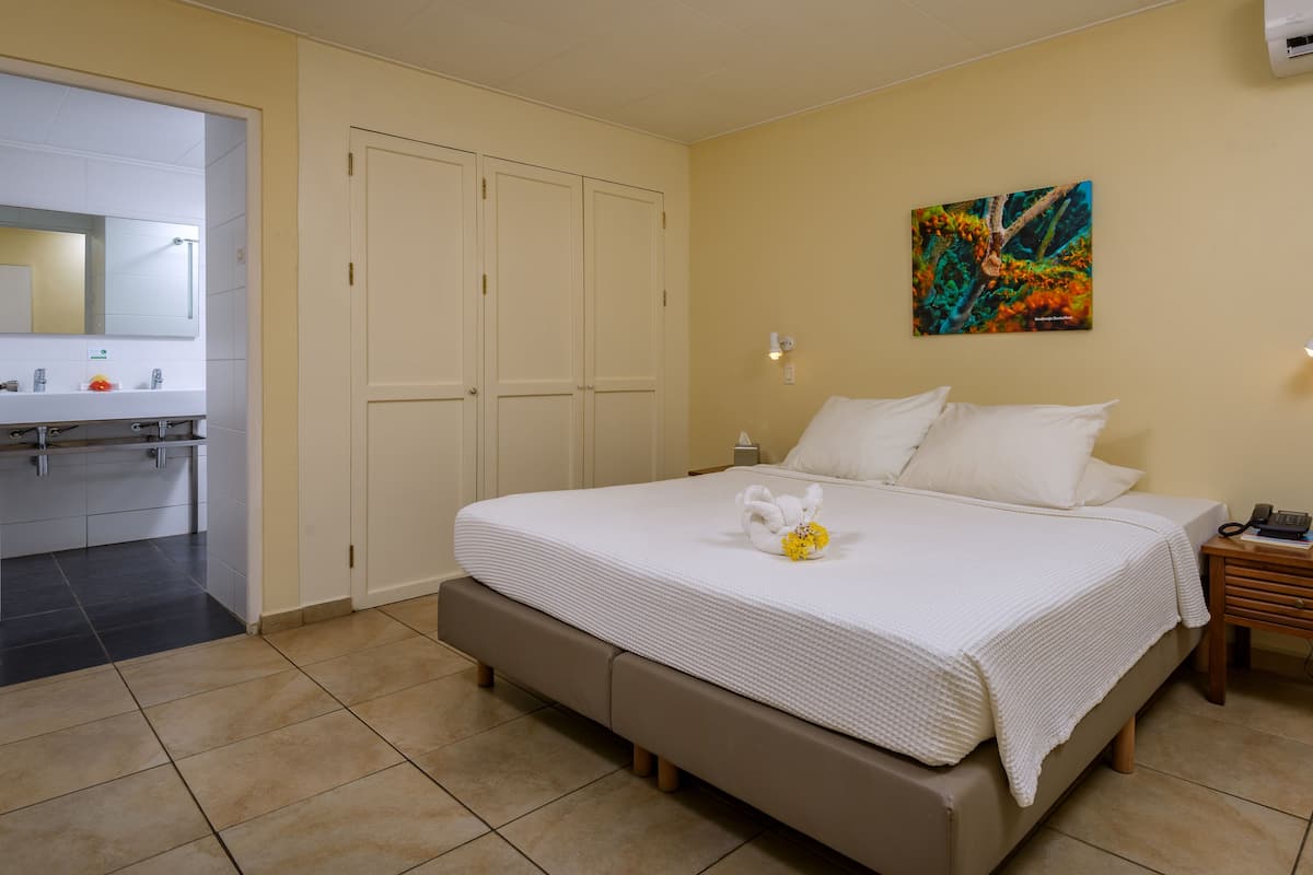 A hotel room with a bed, bedside table, and a bathroom visible through an open door.
