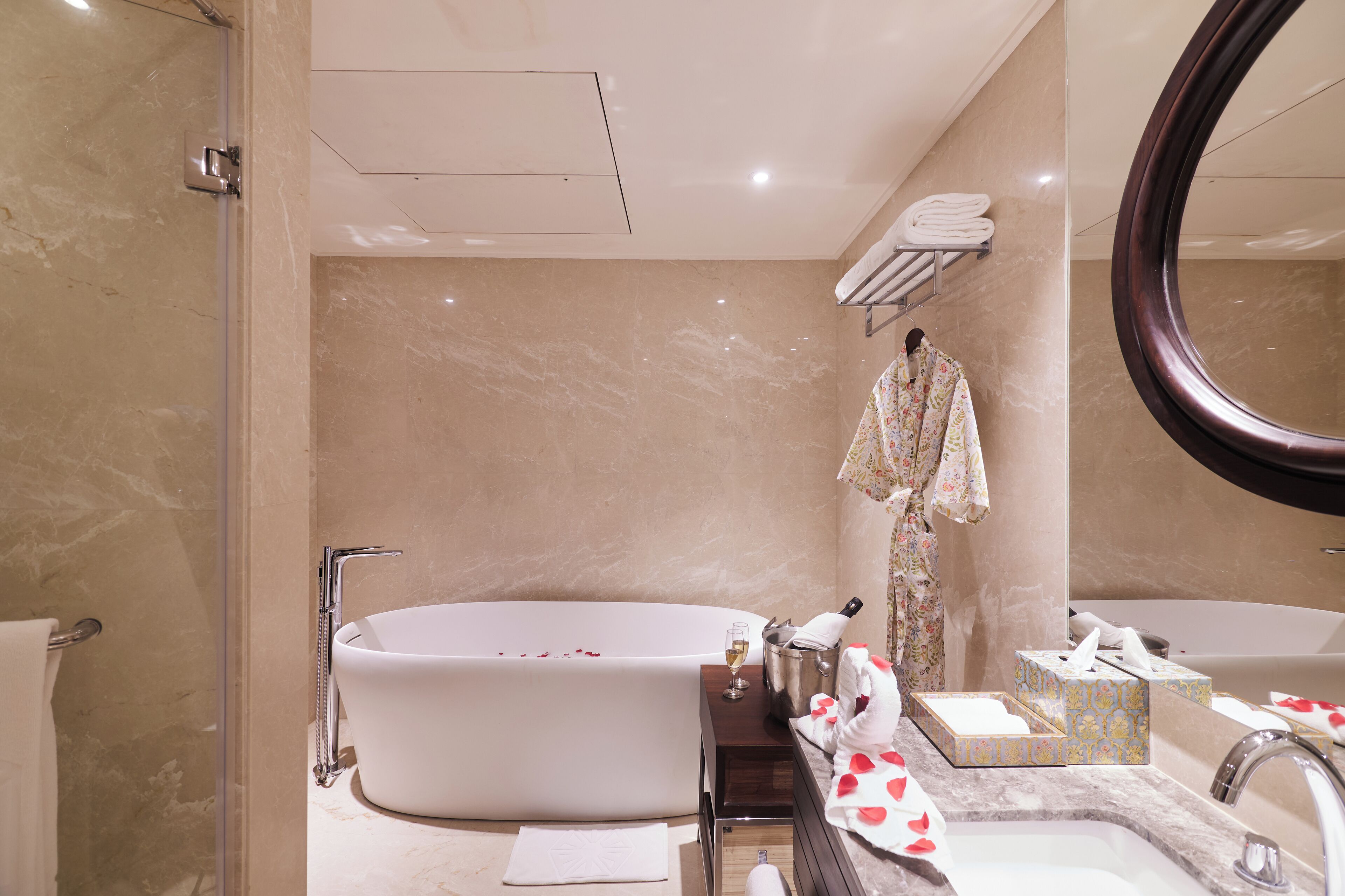 A modern bathroom with a freestanding bathtub, a large mirror, and a vanity with toiletries.