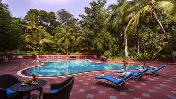Una piscina al aire libre, sombrillas, sillones reclinables de piscina