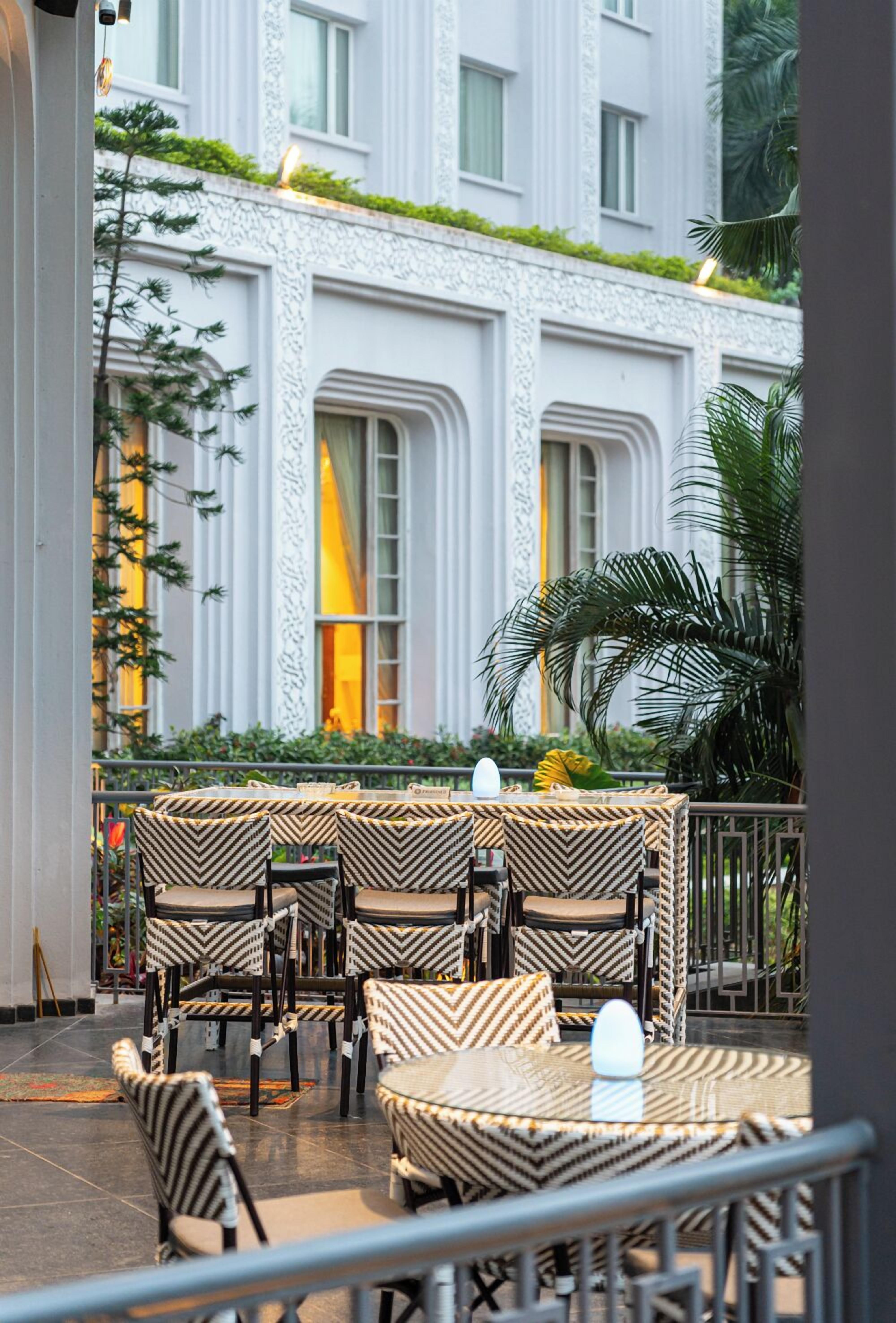 An outdoor seating area with wicker furniture and a view of a building with large windows and decorative elements.