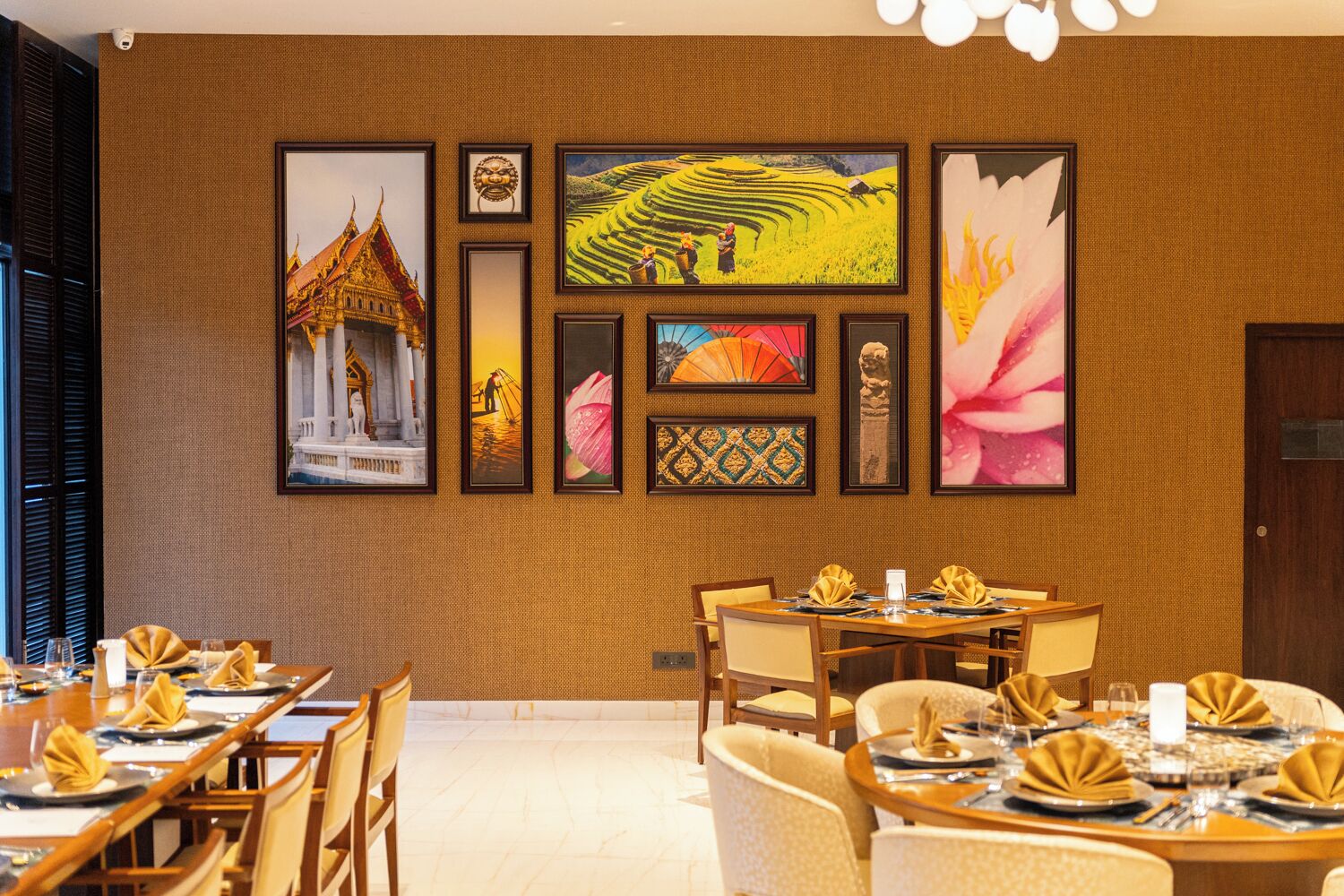 Un restaurante con una larga mesa lista para comer, obras de arte enmarcadas en la pared y un edificio tradicional al fondo.