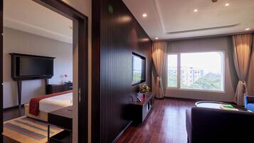 Habitación de hotel con cama, televisión, escritorio y ventana con vista a la ciudad.