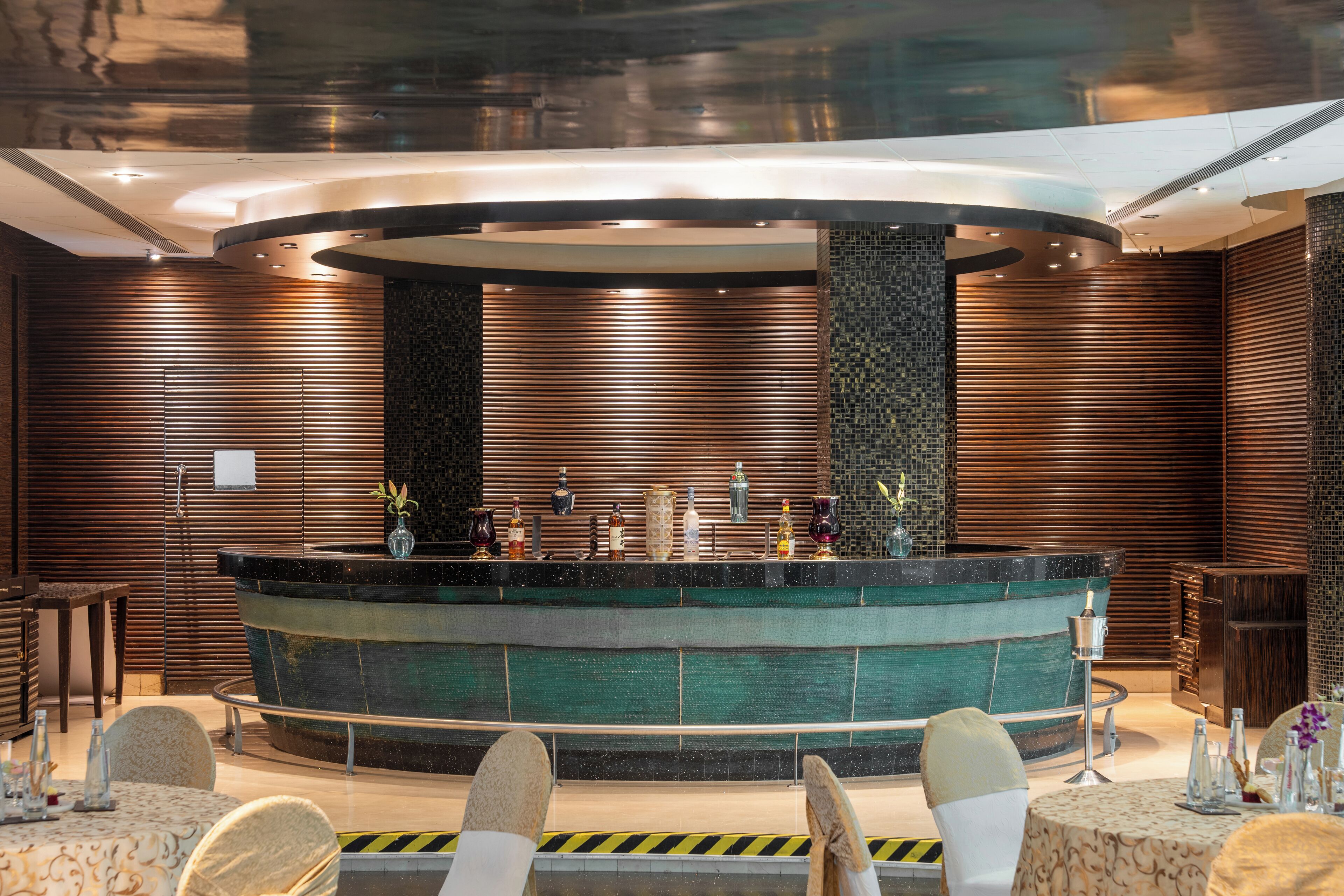 A modern bar area with a circular design, wooden paneling, and a central bar counter.