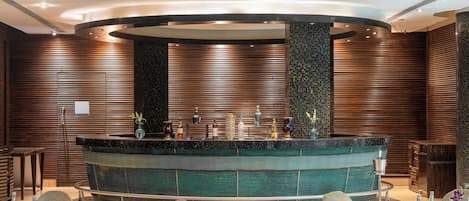 A modern bar area with a circular design, wooden paneling, and a central bar counter.