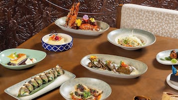A dining table with various dishes, including sushi and a lobster.