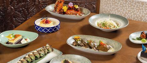 A dining table with various dishes, including sushi and a lobster.