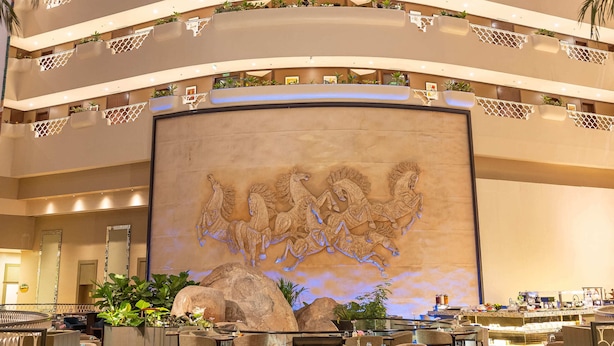 A hotel lobby with a checkered floor, a large mural, and a glass ceiling. - Taj Deccan (Hyderabad)