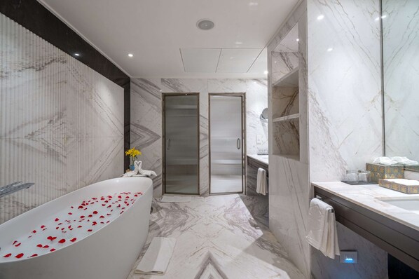 A modern bathroom with a freestanding bathtub, a glass shower enclosure, and a marble floor.