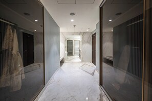 Un pasillo con suelo de mármol, paredes espejadas y vistas al baño.