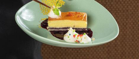 Una persona sosteniendo un plato con una porción de pastel de queso y crema batida.