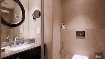 A modern bathroom with a glass shower enclosure, a large mirror, a sink with a towel, and a toilet.