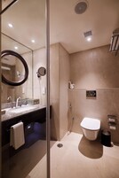 Une salle de bain moderne avec une douche à parois de verre, un grand miroir, un lavabo avec une serviette et des toilettes.