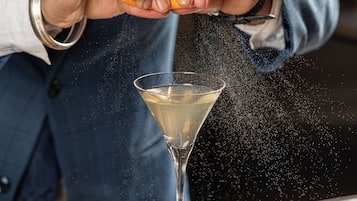 Eine Person gießt eine klare Flüssigkeit in ein Martini-Glas.
