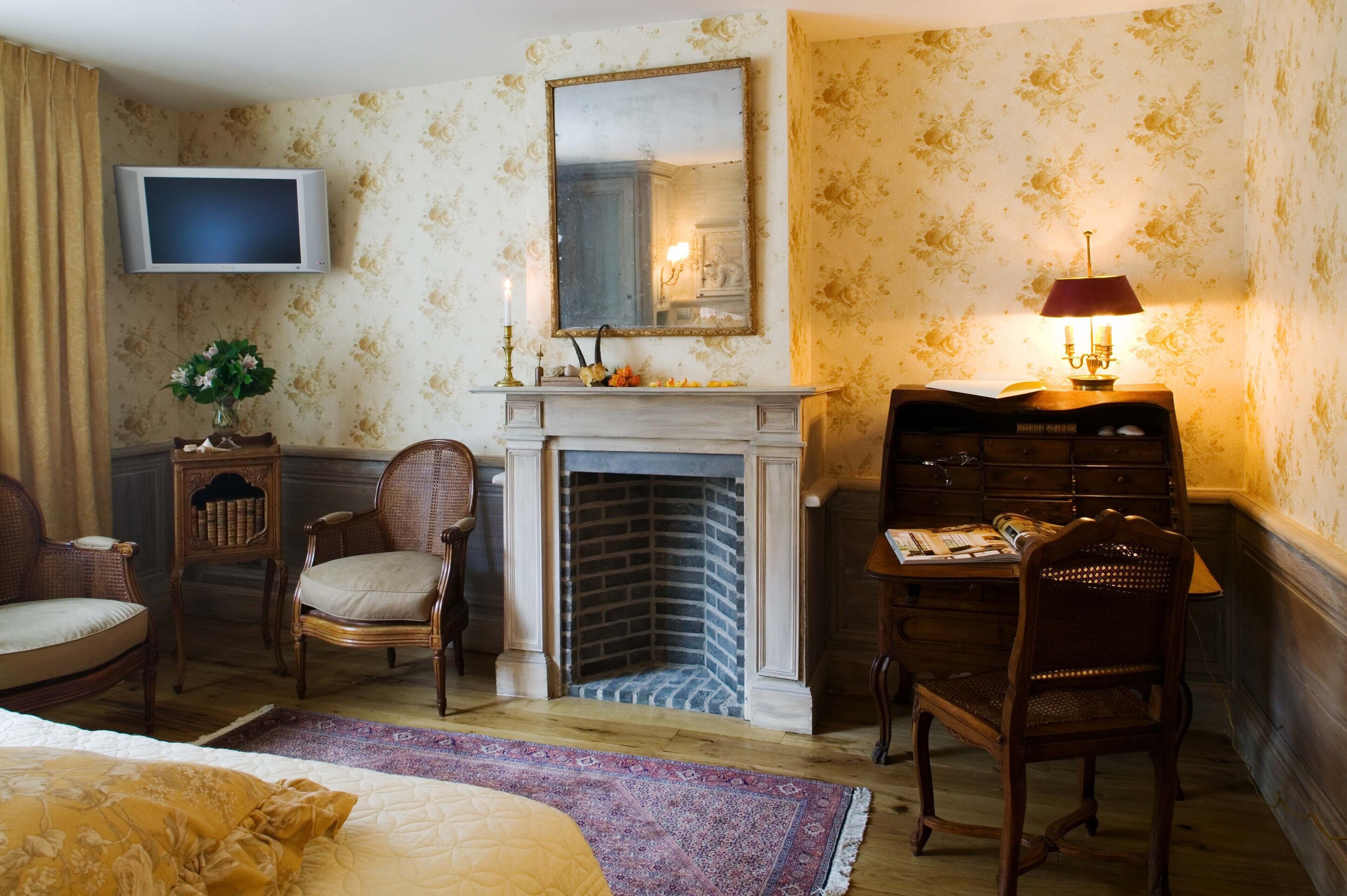 Ein Zimmer mit Kamin, Fernseher und Schreibtisch mit Lampe.