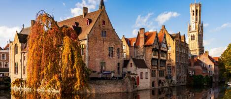 A historic European town with a prominent church tower and a river reflecting the buildings.
