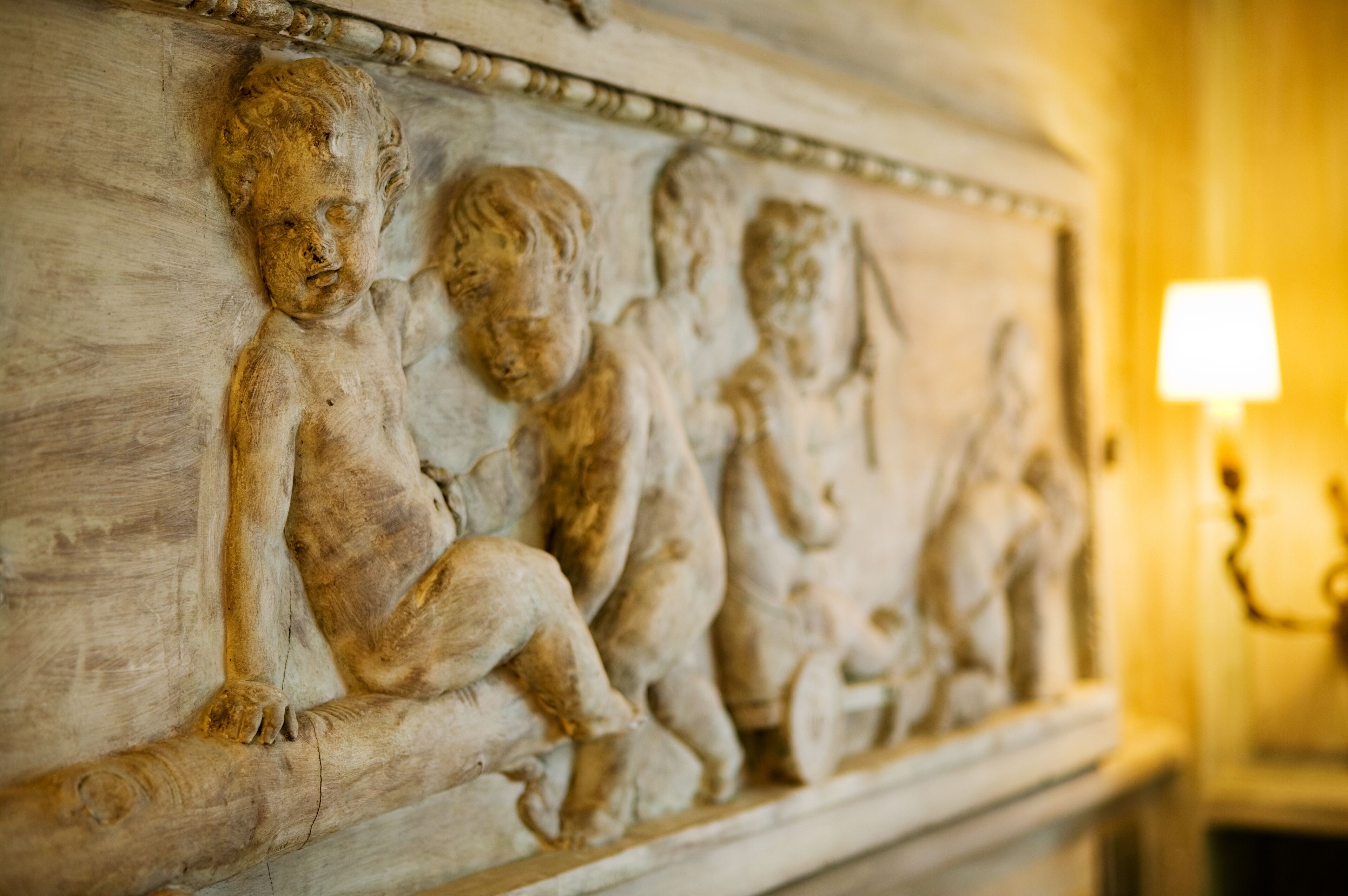 Ein Marmor-Relief mit sitzenden Figuren an einer Wand.