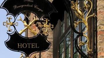 Un letrero de hotel con la palabra 'HOTEL' y 'Rats' escrito, sujeto a un edificio de ladrillo con ventanas amplias.