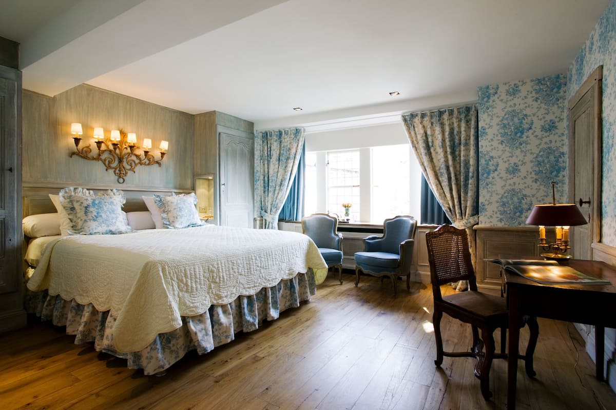 A bedroom with a large bed, a desk, and two chairs.