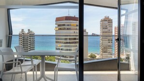 A balcony with a table and chairs, overlooking a coastal cityscape with tall buildings and the sea. - Climia Belroy 4* Superior Hotel (Benidorm)