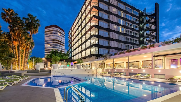A modern hotel with a large pool, outdoor seating, and a well-lit facade. - Climia Belroy 4* Superior Hotel (Benidorm)