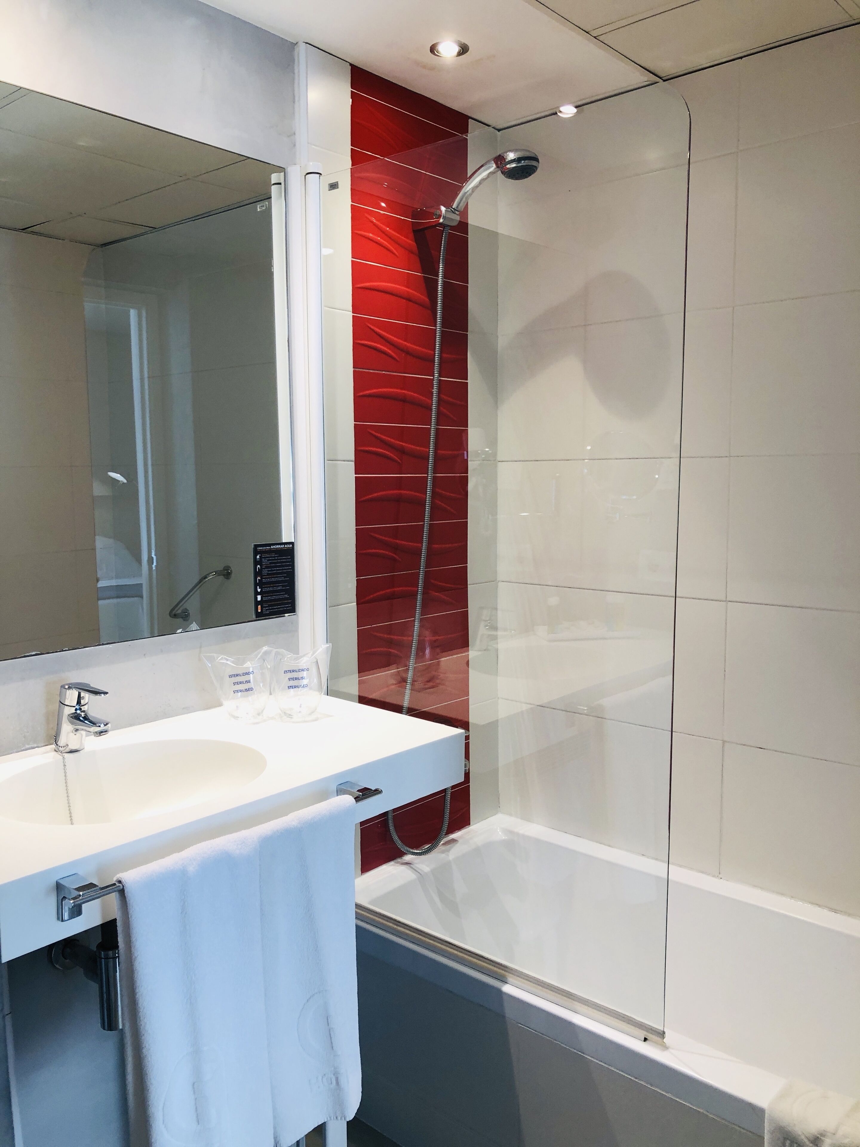Une salle de bain moderne avec un lavabo blanc, un miroir et une douche.