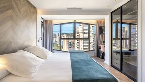 A modern hotel room with a large bed, a view of the city through floor-to-ceiling windows, and a sliding glass door closet. - Climia Belroy 4* Superior Hotel (Benidorm)