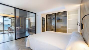 Una habitación de hotel moderna con una cama grande, una pared de vidrio y vista al océano.