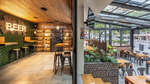 A modern bar area with a wooden ceiling, a green wall with a 'BEER' sign, and a variety of bottles on shelves. - Climia Belroy 4* Superior Hotel (Benidorm)