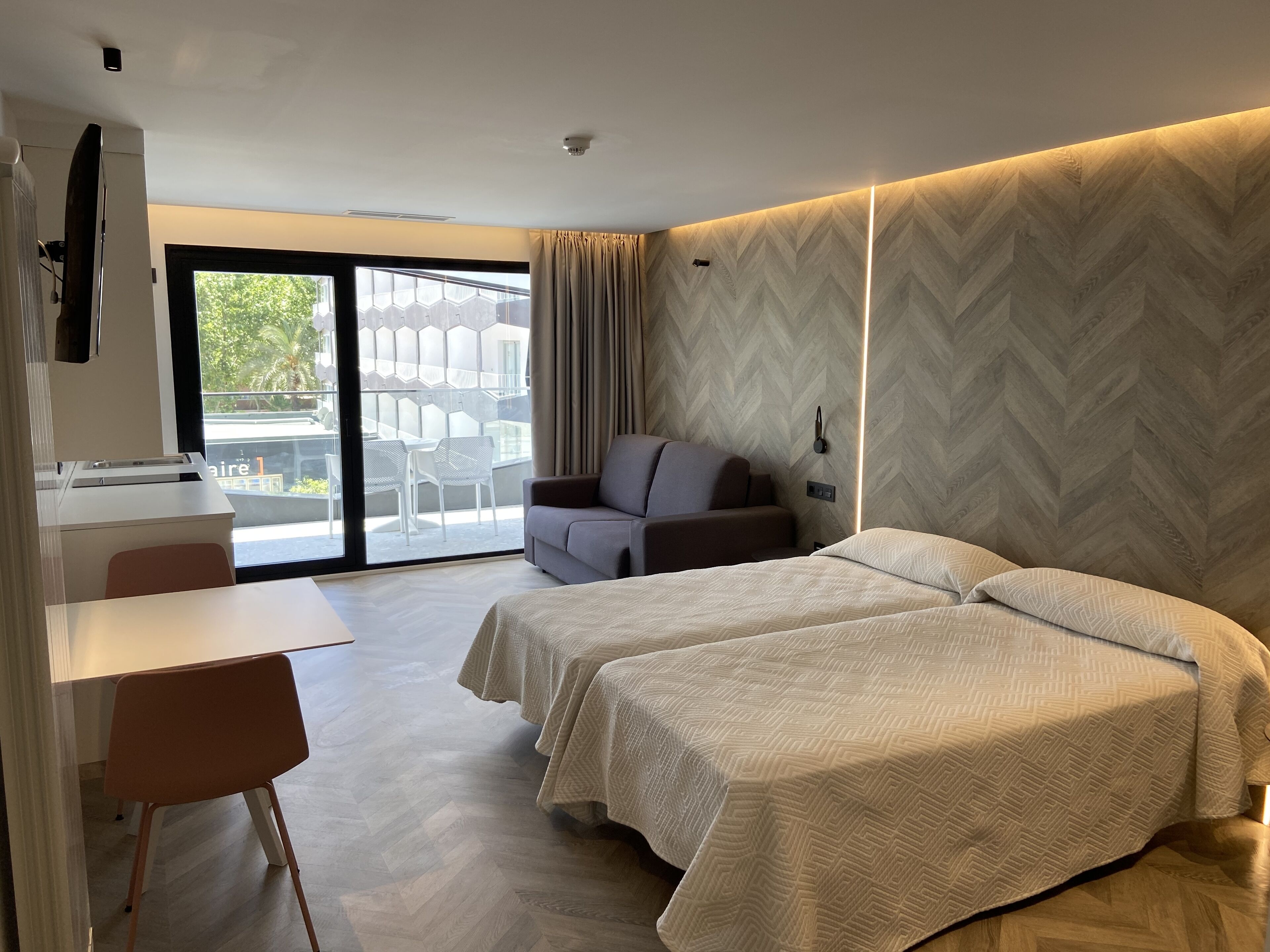 Une chambre d’hôtel moderne avec deux lits, un bureau et une chaise.