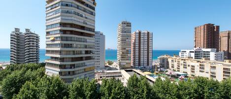 Un hotel de gran altura con múltiples balcones, una zona de piscina y vistas al mar.