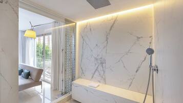 Un baño moderno con pared de mármol, banco integrado, ducha y vistas al exterior.