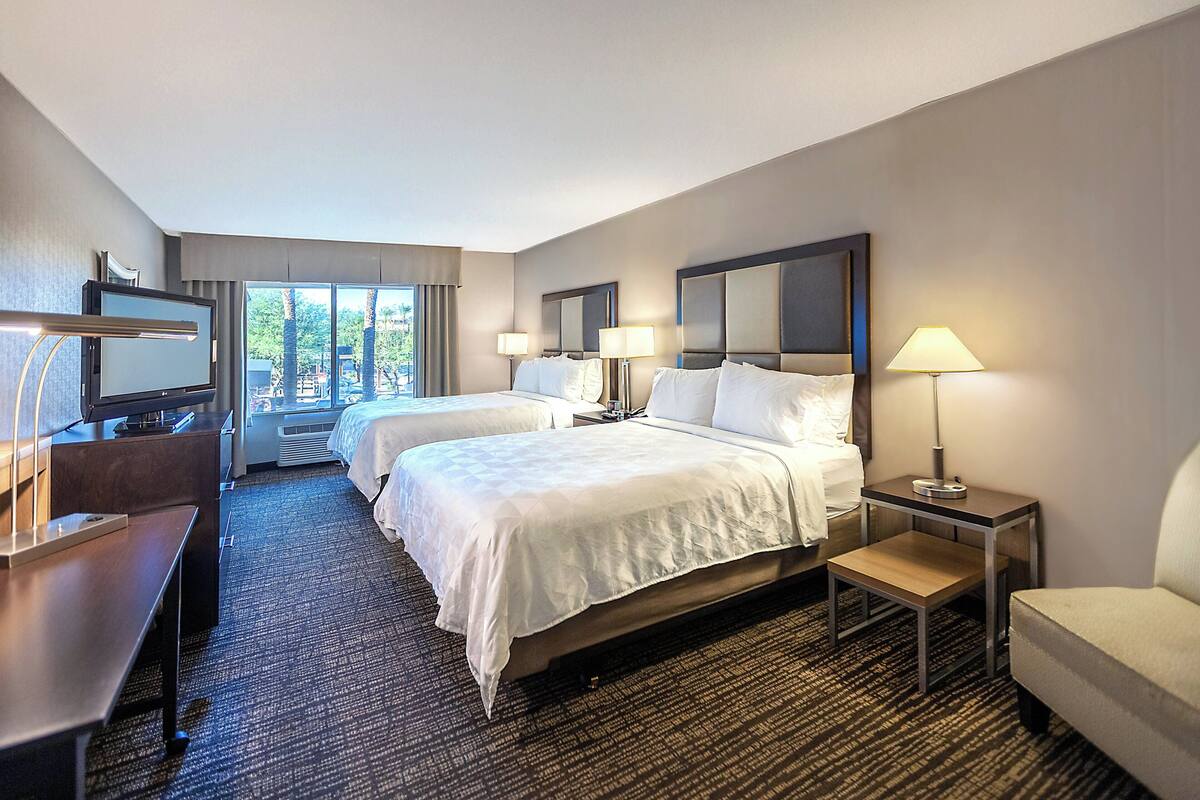 Une chambre d’hôtel avec deux lits, un bureau, une télévision et une chaise.