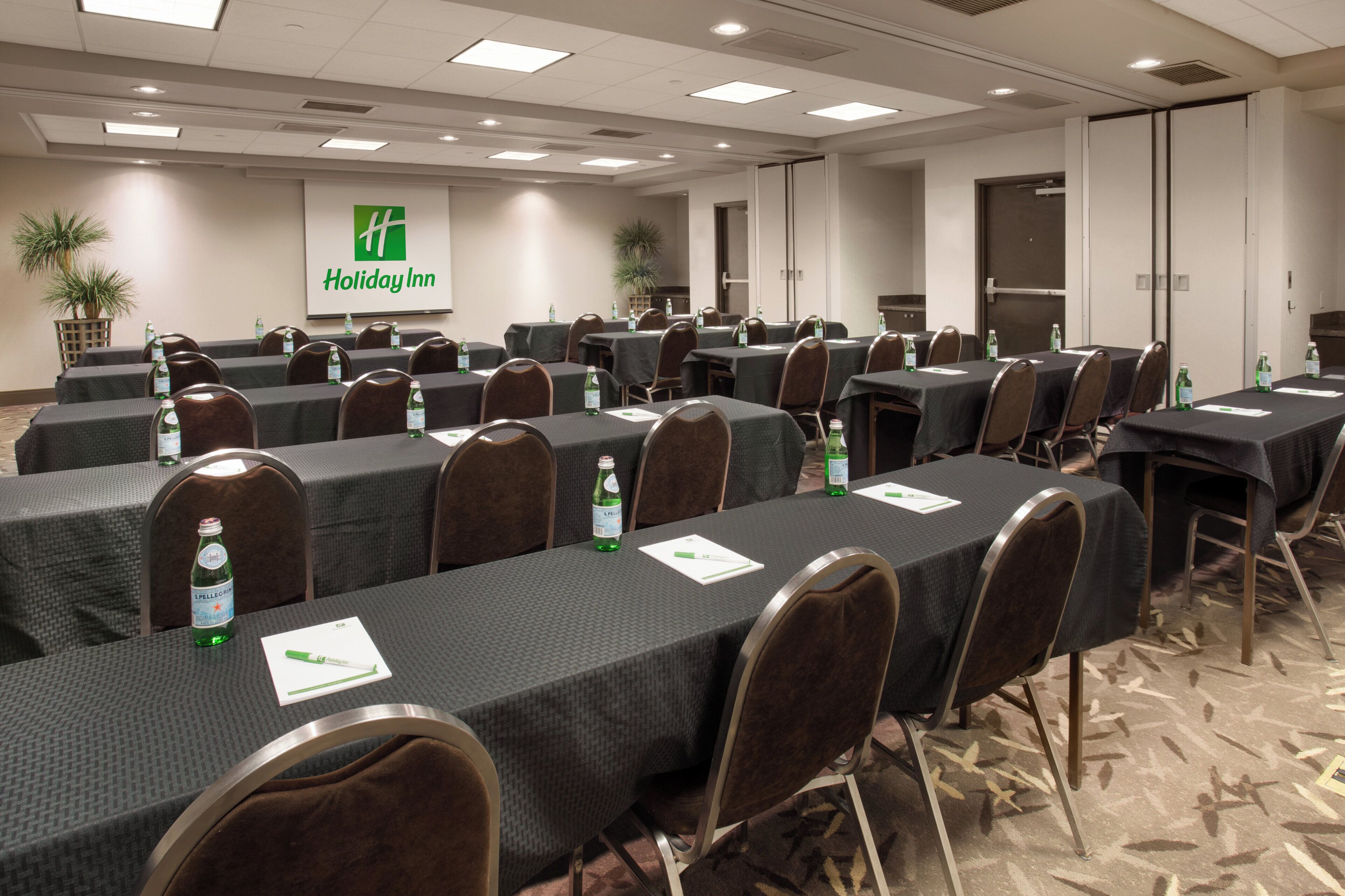 A conference room with multiple tables, chairs, and water bottles.