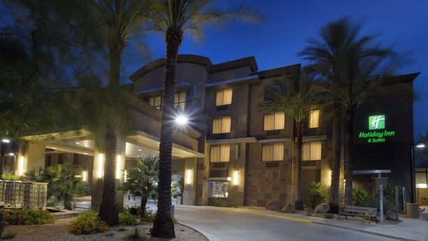 A Holiday Inn & Suites building with a curved facade, multiple balconies, and a well-lit entrance. - Holiday Inn & Suites Scottsdale North - Airpark by IHG (Scottsdale)
