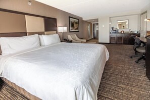 Une chambre d’hôtel avec un grand lit, un bureau, une chaise, un four à micro-ondes et une petite kitchenette.