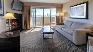 A hotel room with a flat-screen TV, a fireplace, a sofa, a coffee table, and a large window with a view. - Holiday Inn & Suites Scottsdale North - Airpark by IHG (Scottsdale)