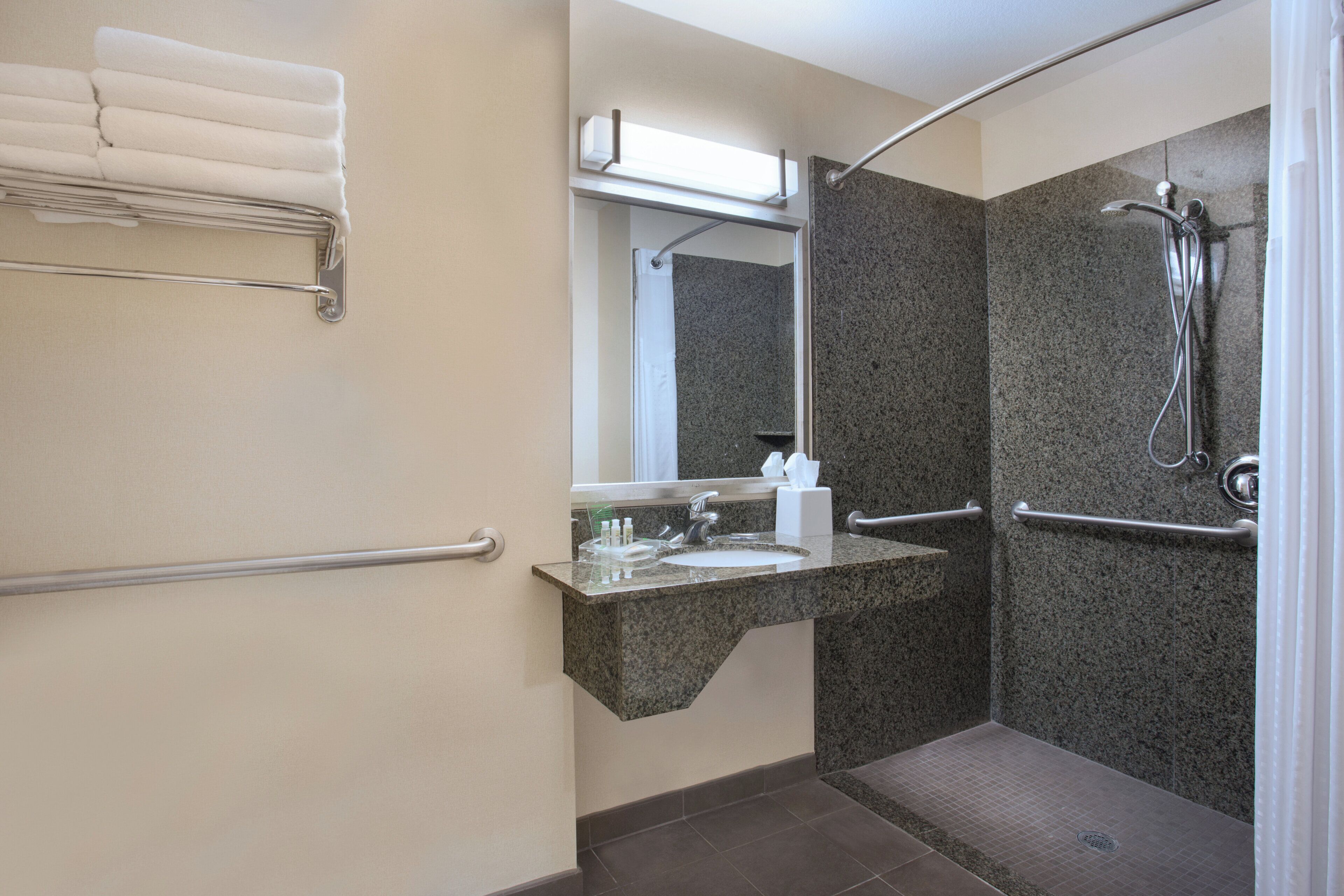Ein Badezimmer mit Dusche, Waschbecken, Spiegel und Handtuchhalter.