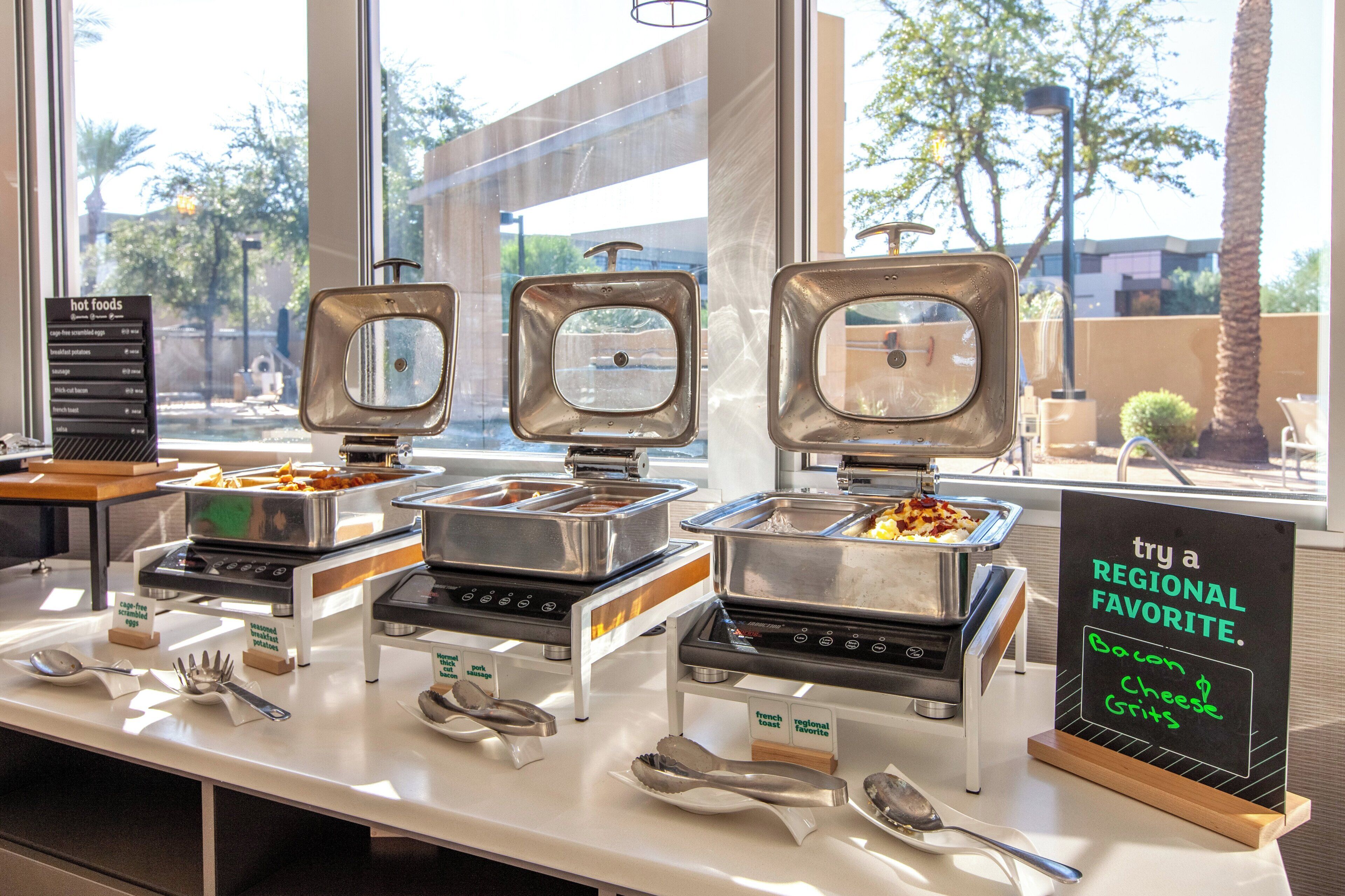 Een buffetopstelling met verschillende food stations, bestek en een bordje dat regionale specialiteiten aanbeveelt.