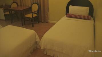 A hotel room with two single beds, a desk, a chair, and a television.