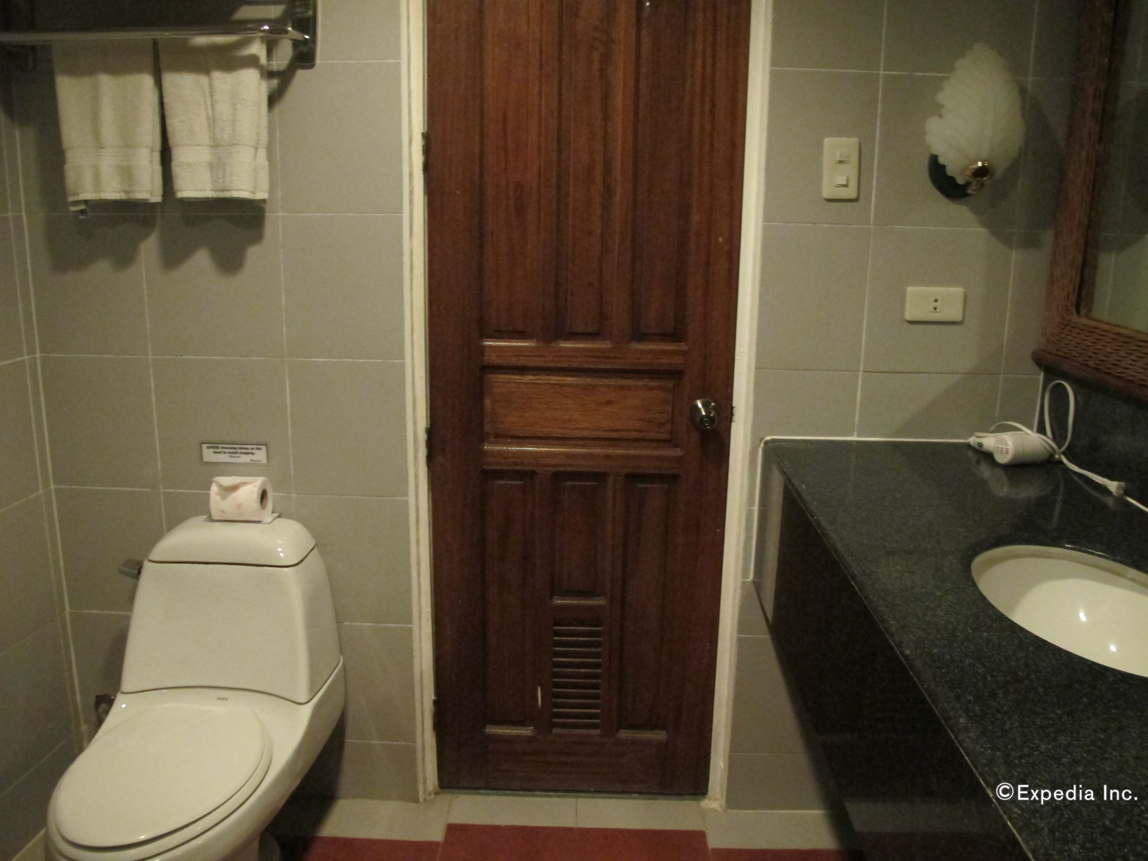 A bathroom with a toilet, a sink, and a wooden door.