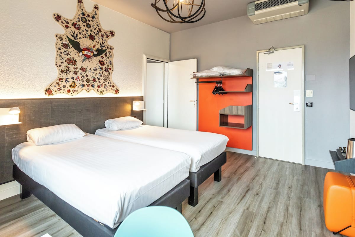 A hotel room with a large bed, a wardrobe, a desk, and a wall-mounted artwork.