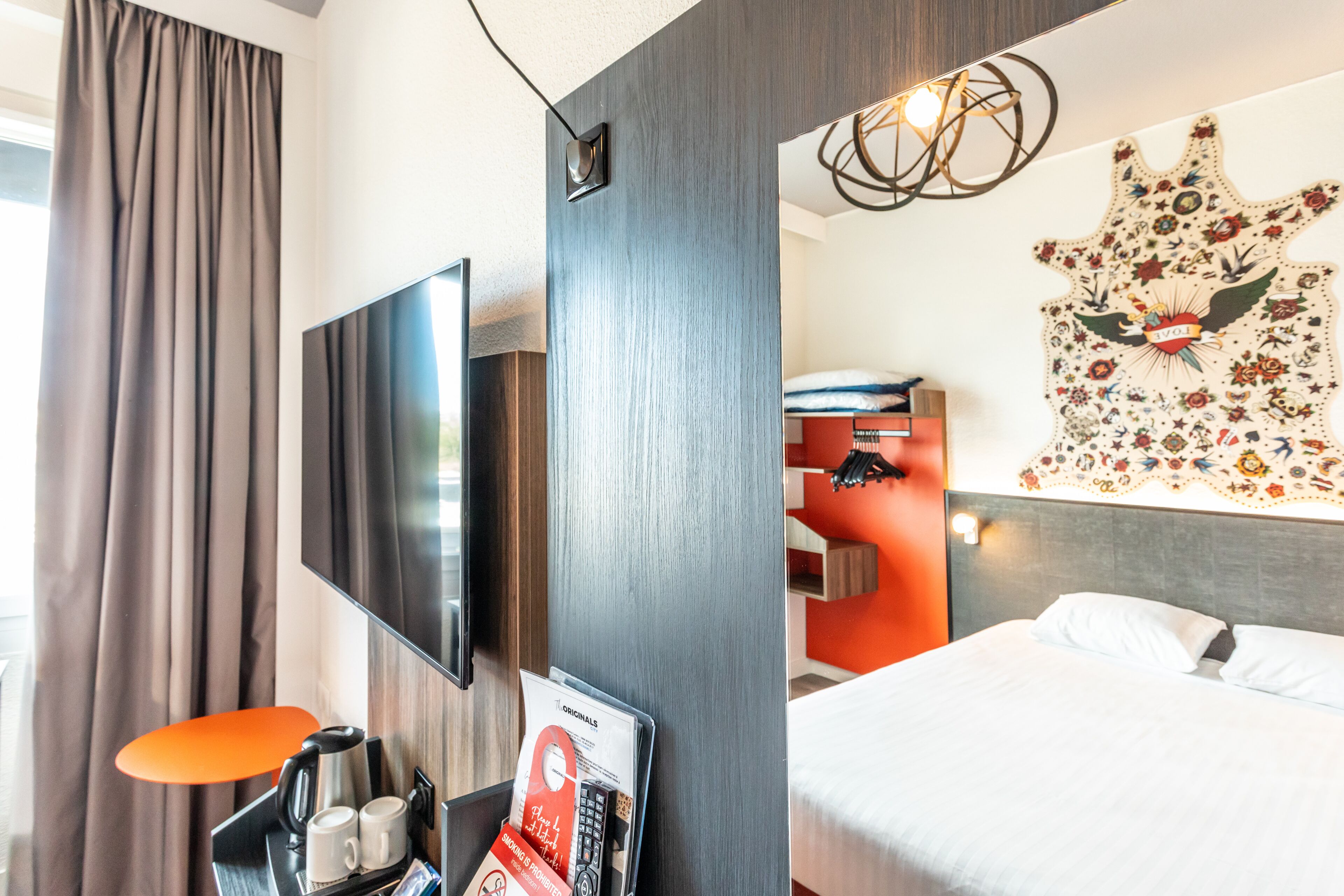 Habitación de hotel con televisión de pantalla plana, cama, obra de arte en la pared y estación de café.