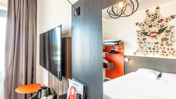 Habitación de hotel con televisión de pantalla plana, cama, obra de arte en la pared y estación de café.
