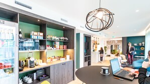 A modern interior with a kitchen area, a dining table with a laptop, and a refrigerator stocked with beverages.