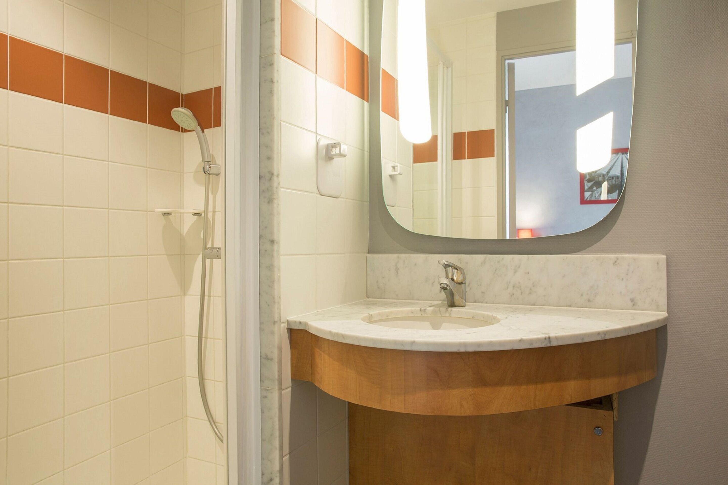 Un baño con ducha, lavamanos y espejo.
