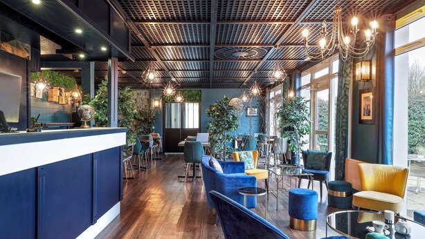 Un intérieur moderne comprenant un comptoir d’accueil, un espace détente et de grandes fenêtres.